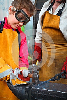 Girl in goggles and yellow apron with hammer photo