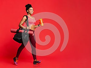 Girl going to gym with yoga mat, bag and shaker