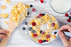 Girl is going to have breakfast cereal with milk and fresh berries. Healthy summer breakfast. First-person view. Healthy