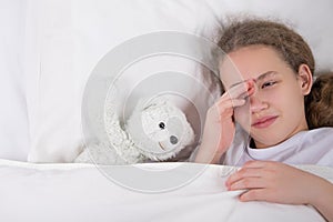 Girl is going to sleep, lies in bed next to a white teddy bear