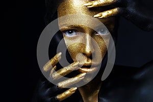 Girl with gold and black paint on face and body. Isolation on a black background in the studio