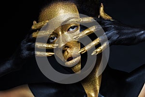 Girl with gold and black paint on her face and body