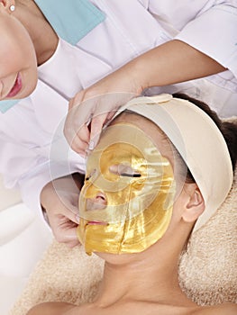 Girl with gold facial mask.