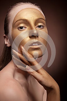 Girl with gold fashion make up on brown background