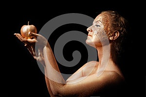 Girl with golden bodyart posing with golden apple