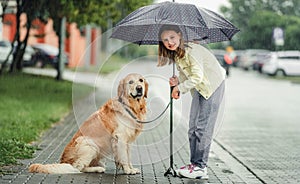 Girl with golden retriever dog in rainy day