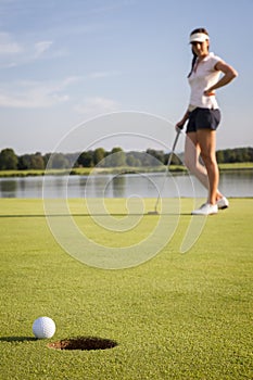 Girl golf player putting on green.