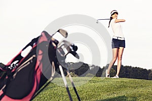 Girl golfer hitting the ball on golf course.