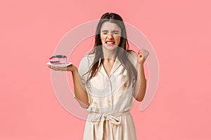 Girl gonna puke from disgusting taste of cake. Disappointed young woman try eating dessert and grimacing, squinting from