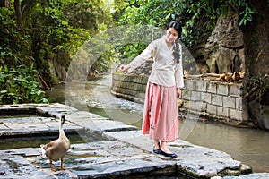 Girl and goose playing by the river