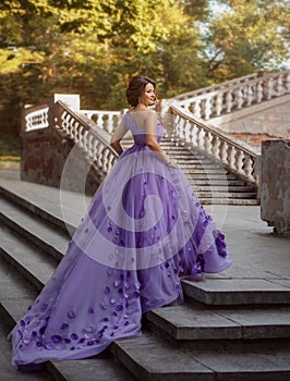 Girl in gorgeous purple long dress standing on the stairs