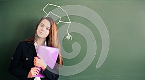 Girl in graduate hat with folder in hand on green chalkboard background. Online education and e-learning concept. Back to school 