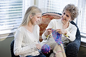 Girl with grandmother knitting in loving room