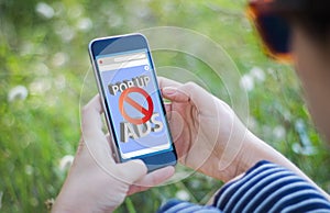 girl in grass holding her smartphone with ads blocker