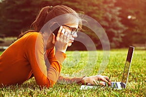 Girl in grass using laptop and smart phone