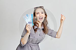 A girl in a gray dress holds plane tickets and rejoices