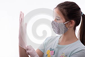 Girl with a gray mask on her face puts protective gloves on her hands