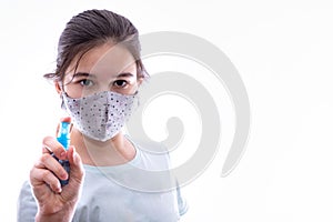 Girl with a gray mask on her face splashes with antiseptic