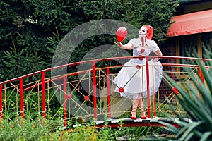 A girl with greasepaint in a white dress with red hair.