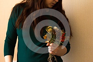 A girl in a green jacket with a bouquet of dried flowers in her hands