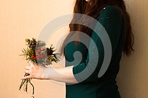 A girl in a green jacket with a bouquet of dried flowers in her hands