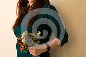 A girl in a green jacket with a bouquet of dried flowers in her hands