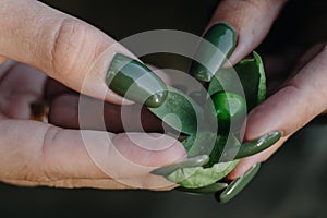 Girl with green manicure holds a green cranberry in her hands.