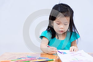 Girl in green shirt was sitting and coloring it with wood paint on drawing paper. Child 3-4 years old have fun making crafts.