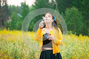 A girl in a green skirt on a flower meadow blowing bubbles