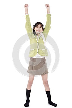 Girl in green sweater and skort standing with arms rasied, happy