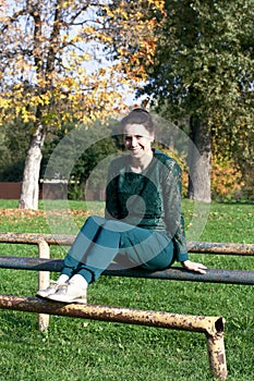 The girl in a green tracksuit. On a Sportsground. Does physical exercise