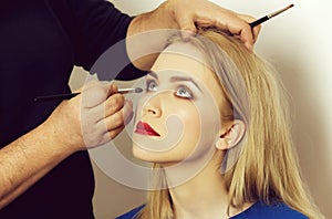 Girl with grey eyes and red lips getting makeup