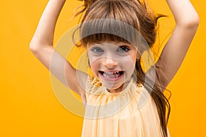 Girl grimaces and twists her hair on a yellow background