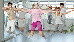 Girl with group of youthful friends bob up and down during dance class