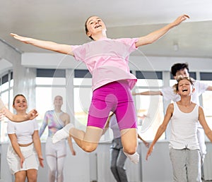 Girl with group of youthful friends bob up and down during dance class