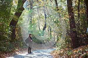 Girl with gun in his hands stands in the autumn forest