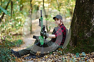 Girl with gun sitting near tree