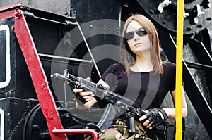 Girl with a gun sitting on the running board of a steam locomotive