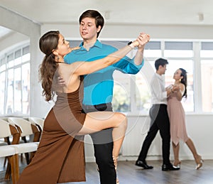 Girl and guy dancing slow ballroom dance during group class in choreography studio