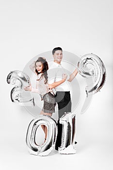 Girl and guy dressed in a stylish smart clothes are holding balloons in the shape of numbers 2019 on a white background