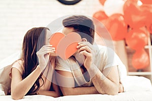 A Girl And A Guy Kiss Holding Red Heart Origami. photo