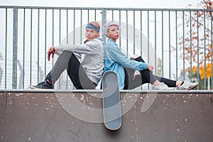 Girl with a guy sitting back to back in the dispersal in a skate park