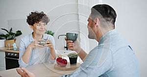 Girl and guy talking drinking coffee laughing at home at kitchen table