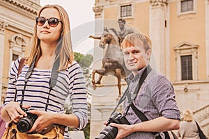 Girl and guy tourists with cameras in Italy Rome Capitoline at statue with rider. toning beige, sand