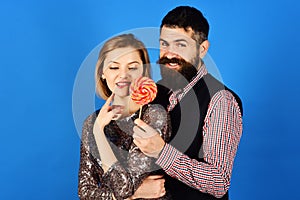 Girl and guy with tricky smiling faces eat colorful candy.
