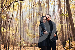 The girl and the guy are walking in the autumn forest