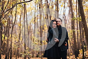 The girl and the guy are walking in the autumn forest