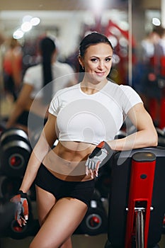 Girl in gym smiling happy standing by fitness machines