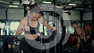 A girl in the gym trains. Sexy young woman is engaged in simulators in the gym. Beautiful sport figure.