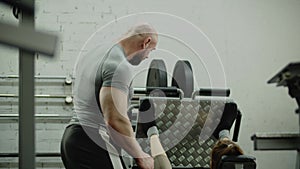 A girl in the gym under the guidance of man fitness instructor does an exercise for her legs within a weight of barbell